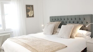 A neatly arranged bedroom with a large bed, a tufted headboard, and a bedside table. - Brand new 2 bedroom apartment by RIO 2 and Matadero (Madrid)