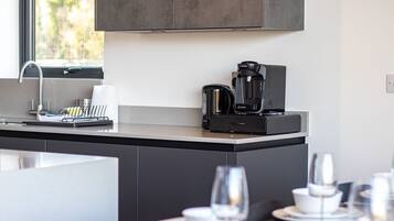 Eine moderne Küche mit Kaffeemaschine, Spüle und einem Fenster mit Blick auf Bäume.