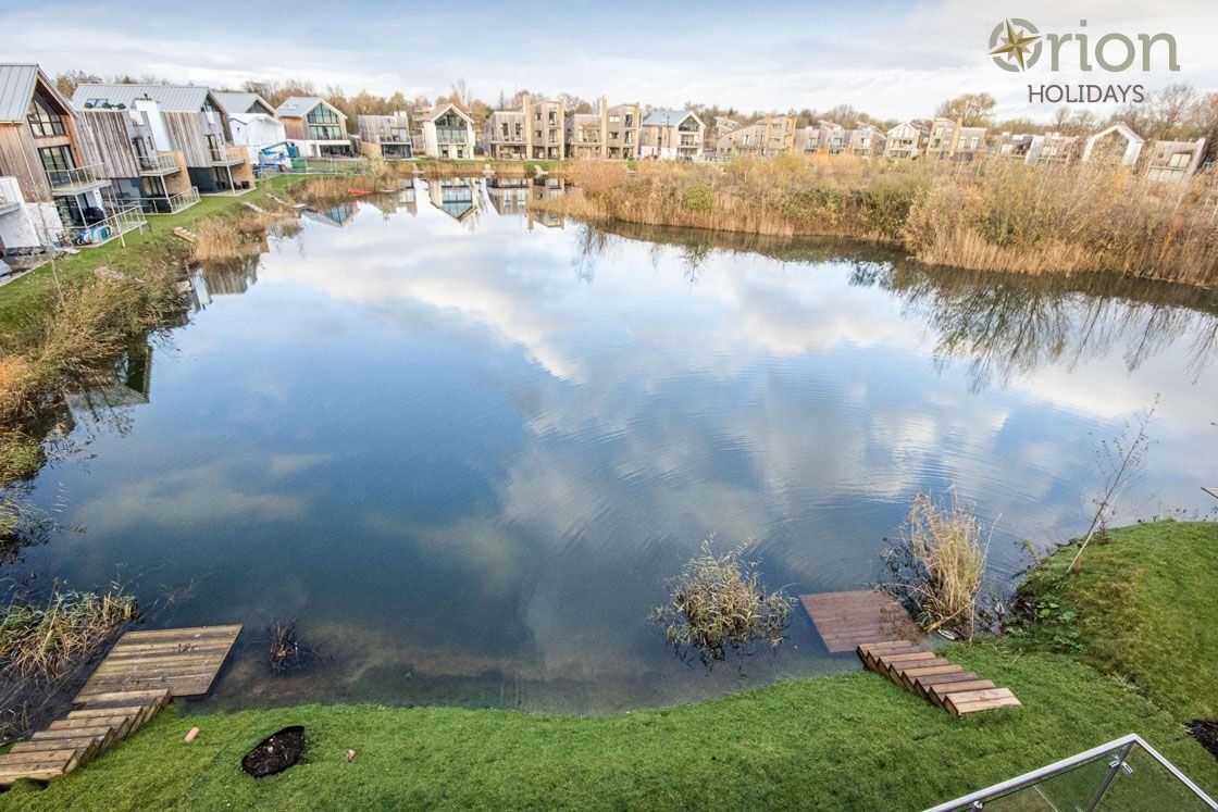 A tranquil lake with wooden docks, surrounded by modern buildings with large windows and balconies.