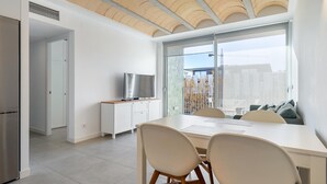A modern kitchen with a large window, a dining area with a table and chairs, and a TV on a cabinet. - Perfect space in Platja d'Aro, Costa Brava (Platja d'Aro)
