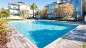 A modern pool area with a wooden deck, surrounded by contemporary buildings and autumn foliage. - Perfect space in Platja d'Aro, Costa Brava (Platja d'Aro)
