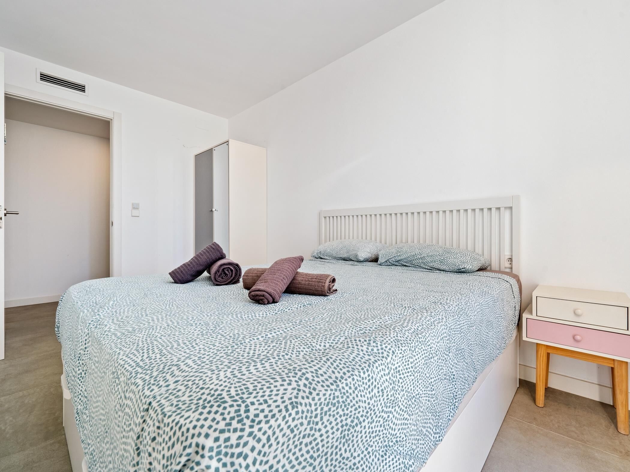 Une chambre à coucher avec un lit, des oreillers, une table de chevet et une porte.