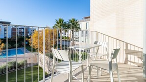 A balcony with a table and chairs, a pool, and a view of other buildings. - Perfect space in Platja d'Aro, Costa Brava (Platja d'Aro)