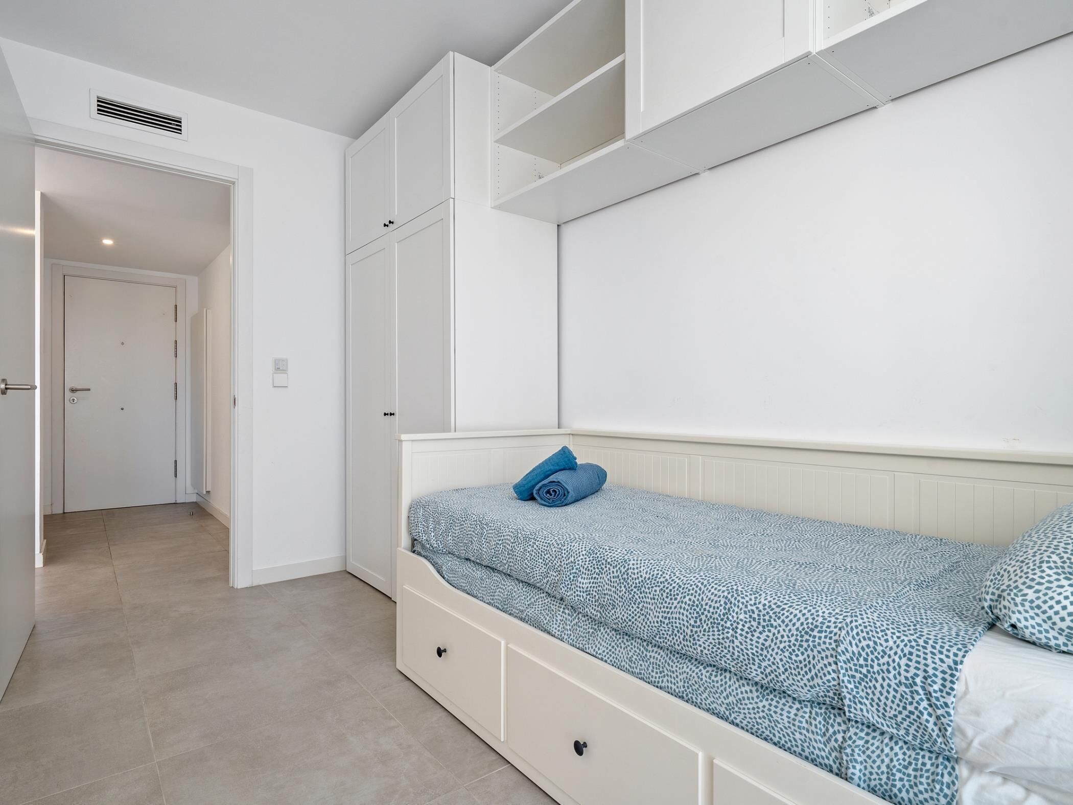 Une chambre à coucher comprenant un lit, une armoire et une porte donnant sur une autre pièce.