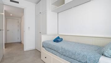 Une chambre à coucher comprenant un lit, une armoire et une porte donnant sur une autre pièce.