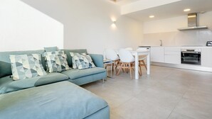 A modern living room with a sofa and chairs, a dining table, and a kitchen area with white cabinets and appliances. - Perfect space in Platja d'Aro, Costa Brava (Platja d'Aro)
