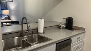 Uma cozinha moderna com uma pia de aço inoxidável, uma lava-louças e uma cafeteira sobre a bancada.