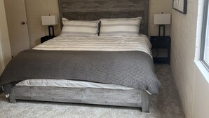 Quarto com cama, ventilador de teto e duas mesas de cabeceira com abajures.