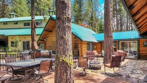 A wooden cabin with a patio area featuring outdoor furniture and a large tree. - Cascade Cabin w/ Mountain View & River Access (Cascade)