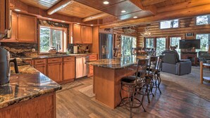 A spacious kitchen with wooden cabinets, granite countertops, and a large island with bar stools. - Cascade Cabin w/ Mountain View & River Access (Cascade)