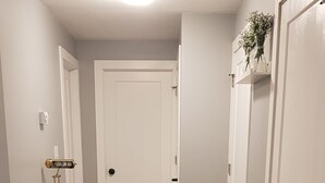 A hallway with a glass-top table and chairs, wooden flooring, and white doors. - Pleasant 1 Bedroom Private Suite in the Meadows (Saskatoon)