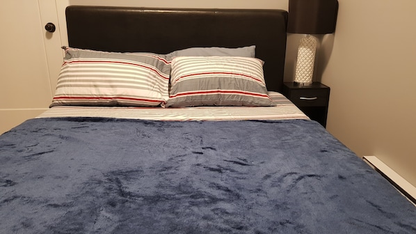 Ein Bett mit gestreifter Bettwäsche und einer blauen Decke.