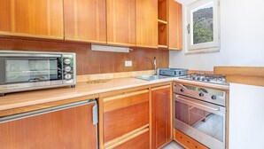 A compact kitchen with wooden cabinets, a built-in oven, a microwave, and a gas stove.