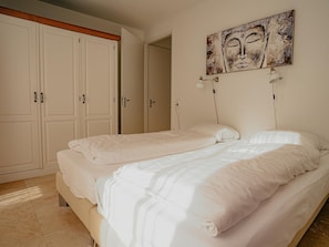 Ein Schlafzimmer mit zwei Betten, einem großen Kleiderschrank und einem an der Wand befestigten Kunstwerk.
