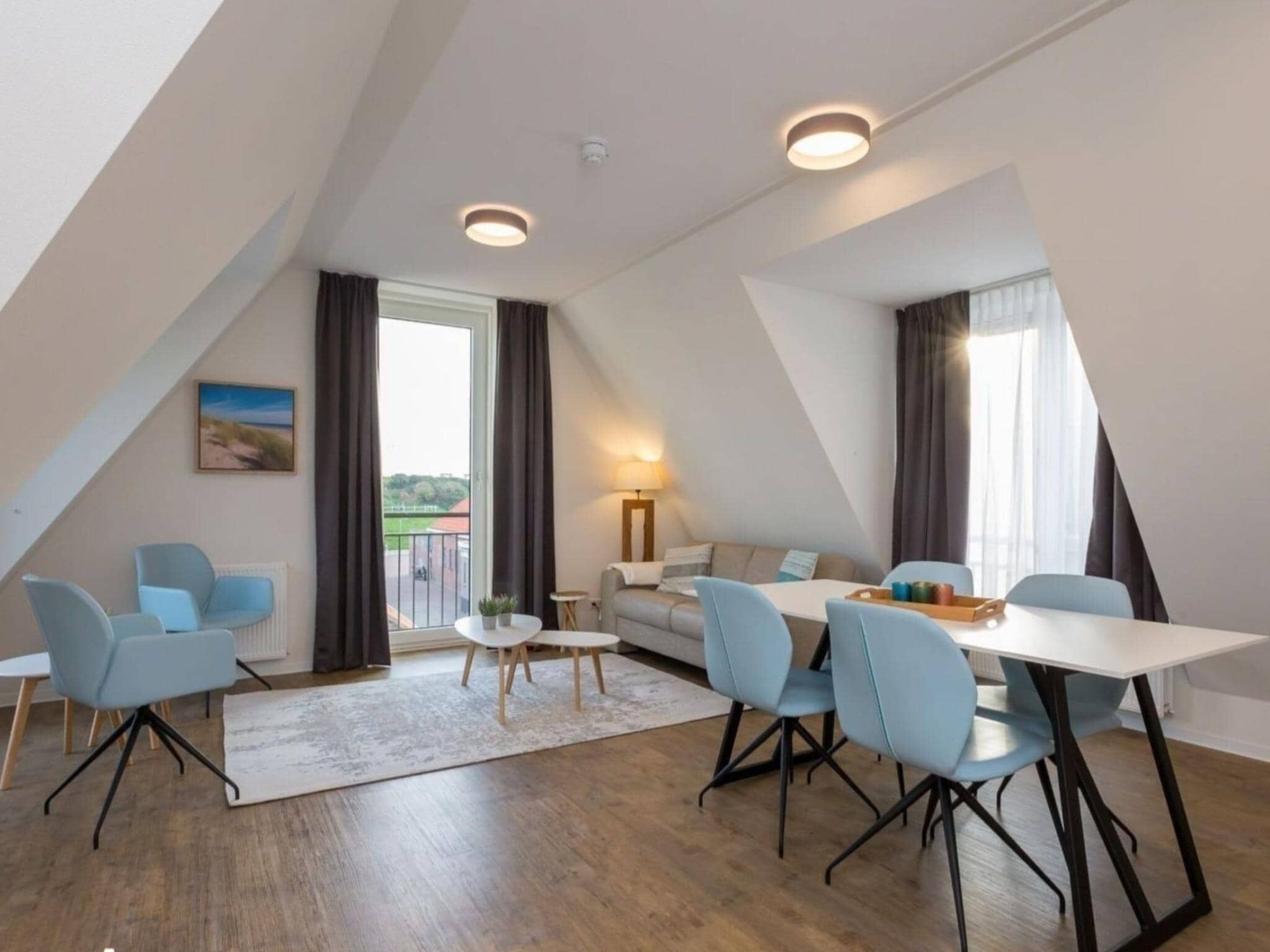 A modern, well-lit room with a dining table, chairs, a sofa, and a lamp.