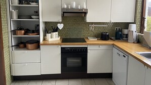 Een kleine keuken met witte kastjes, een zwarte kookplaat en een vaatwasser.
