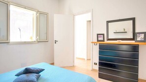 Ein Schlafzimmer mit Bett, Kommode, Spiegel und einer Tür zu einem anderen Raum.