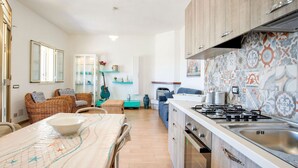 Eine moderne Küche mit Einbauherd, ein Essbereich mit Tisch und Stühlen sowie eine Wohnbereich mit Sofas und einer Gitarre.