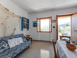 A room with a sofa, a table with a basket, a bookshelf, and a window with a view. - Retreat in Cala Gonone (Cala Gonone)