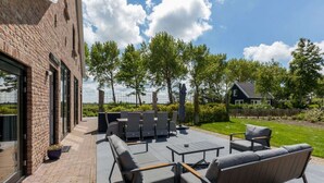Une terrasse extérieure dotée de mobilier moderne, d’un mur en briques et offrant une vue sur le paysage environnant.