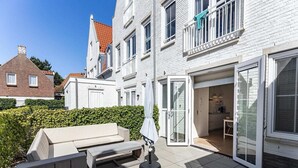 A modern residential building with a patio area, a built-in barbecue, and a sliding glass door leading to a kitchen. - Apartment in Koudekerke near Seabeach (Dishoek)