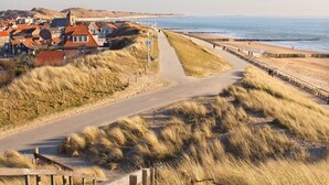 A coastal road with a beach on one side and houses on the other.