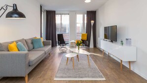 A modern living room with a grey sofa, a white TV stand, and a dining table.