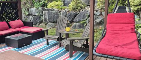 A wooden deck with outdoor seating, including a sofa and chairs, and a swing set.