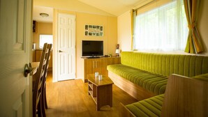 Un espacio habitable compacto con sofá, televisión y zona de comedor.