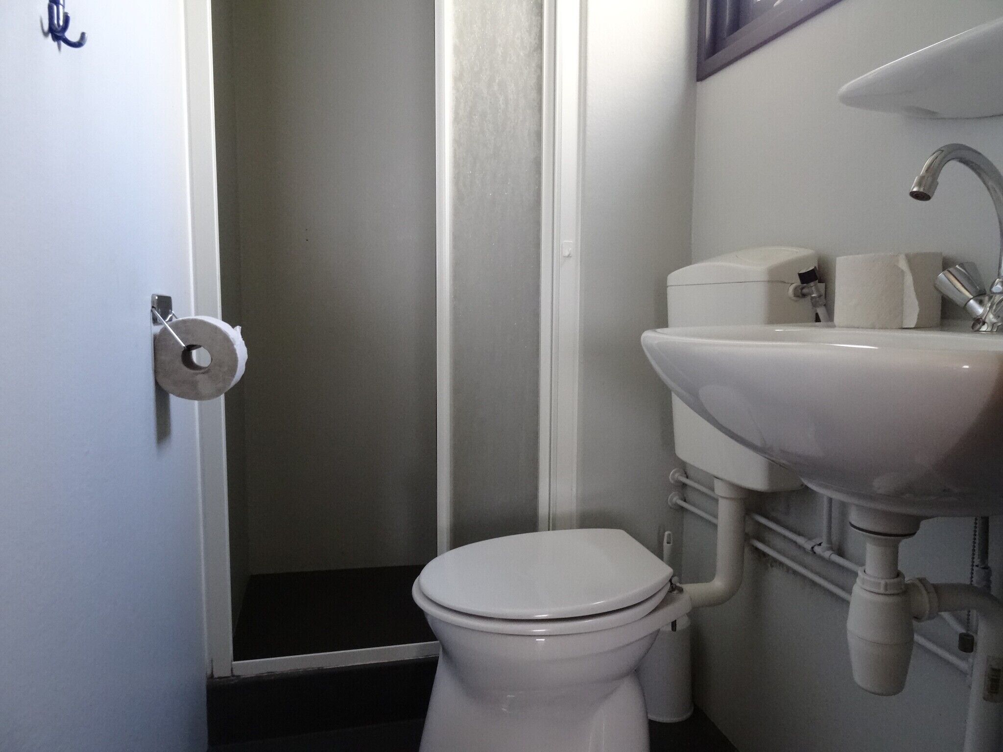 A small bathroom with a toilet, sink, and shower.
