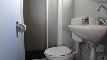 A small bathroom with a toilet, sink, and shower.