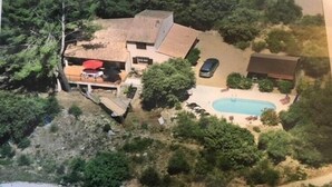 Luftaufnahme eines Anwesens mit Schwimmbad, überdachter Terrasse und einem in der Nähe stehenden Auto.