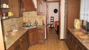 Eine Küche mit Holzausstattung, einem Gasherd, einer Spüle und einem Fliesenboden.