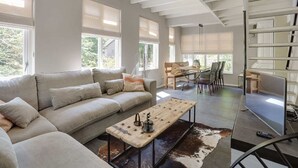A modern living room with a sofa, coffee table, and a dining area with chairs and a table. - Villa in Netherlands with Sauna & Comfort (Uden)