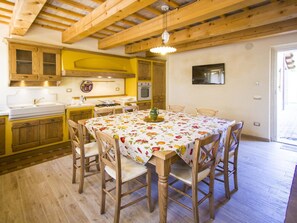 A kitchen with wooden cabinets, a dining table with chairs, and a hanging light fixture.