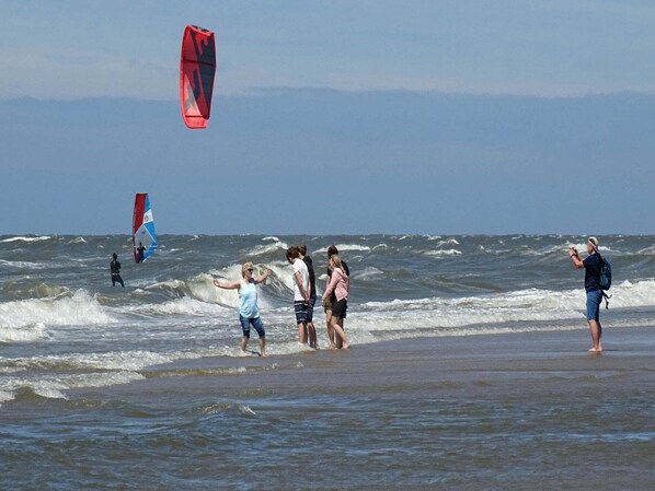 Una playa con gente y cometas.