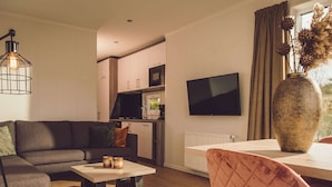 Un salon moderne avec un canapé, une table basse et un téléviseur fixé au mur.