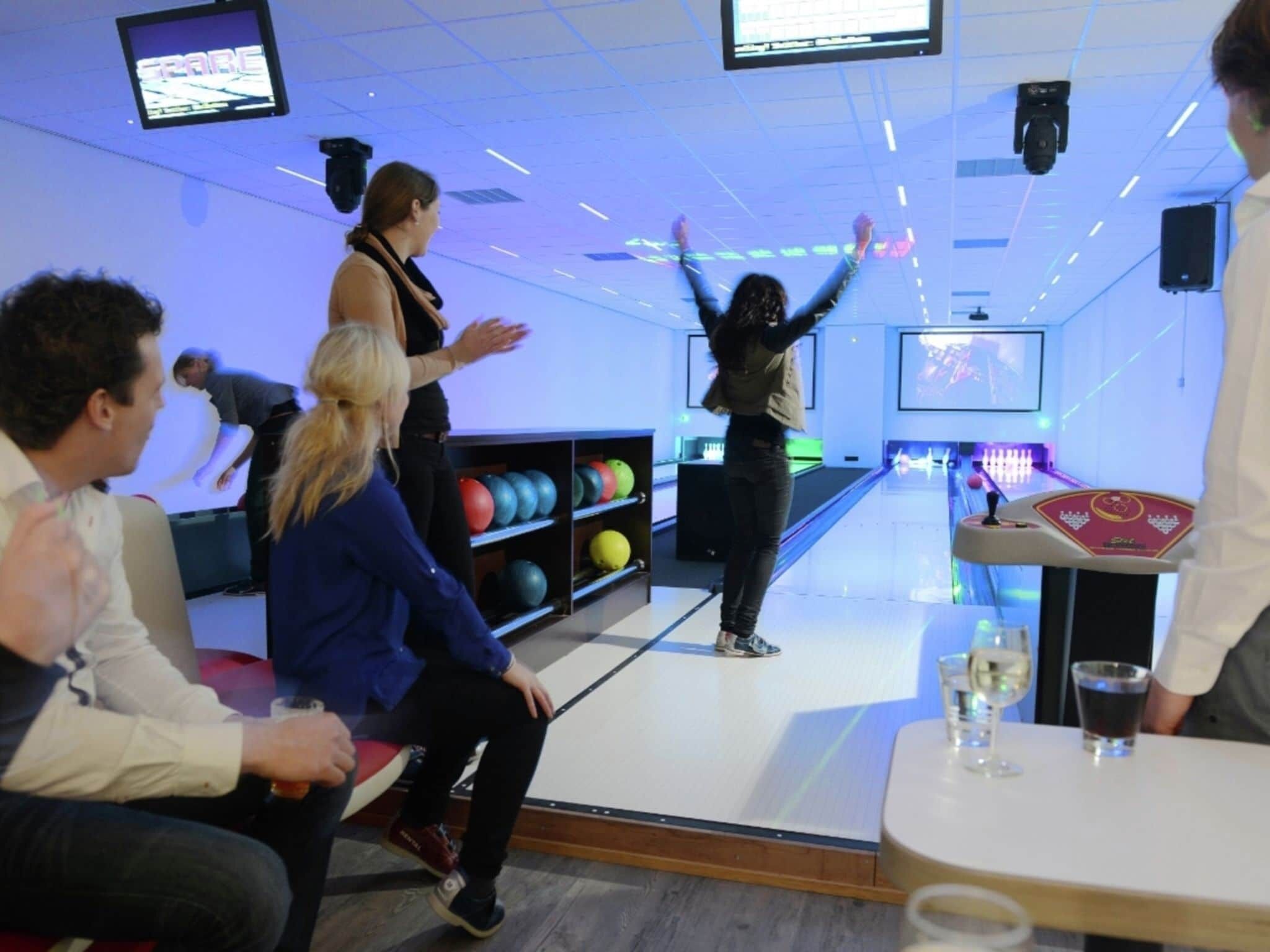Bolera con múltiples pistas, un soporte para pelotas de boliche y un lanzador de bolos.
