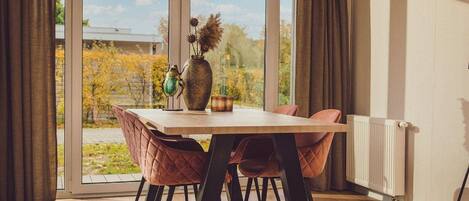 Un comedor con una mesa y sillas, un florero con flores y vistas al exterior.