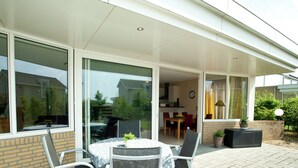 A patio with a table and chairs, a brick wall, and a glass door leading to a dining area.