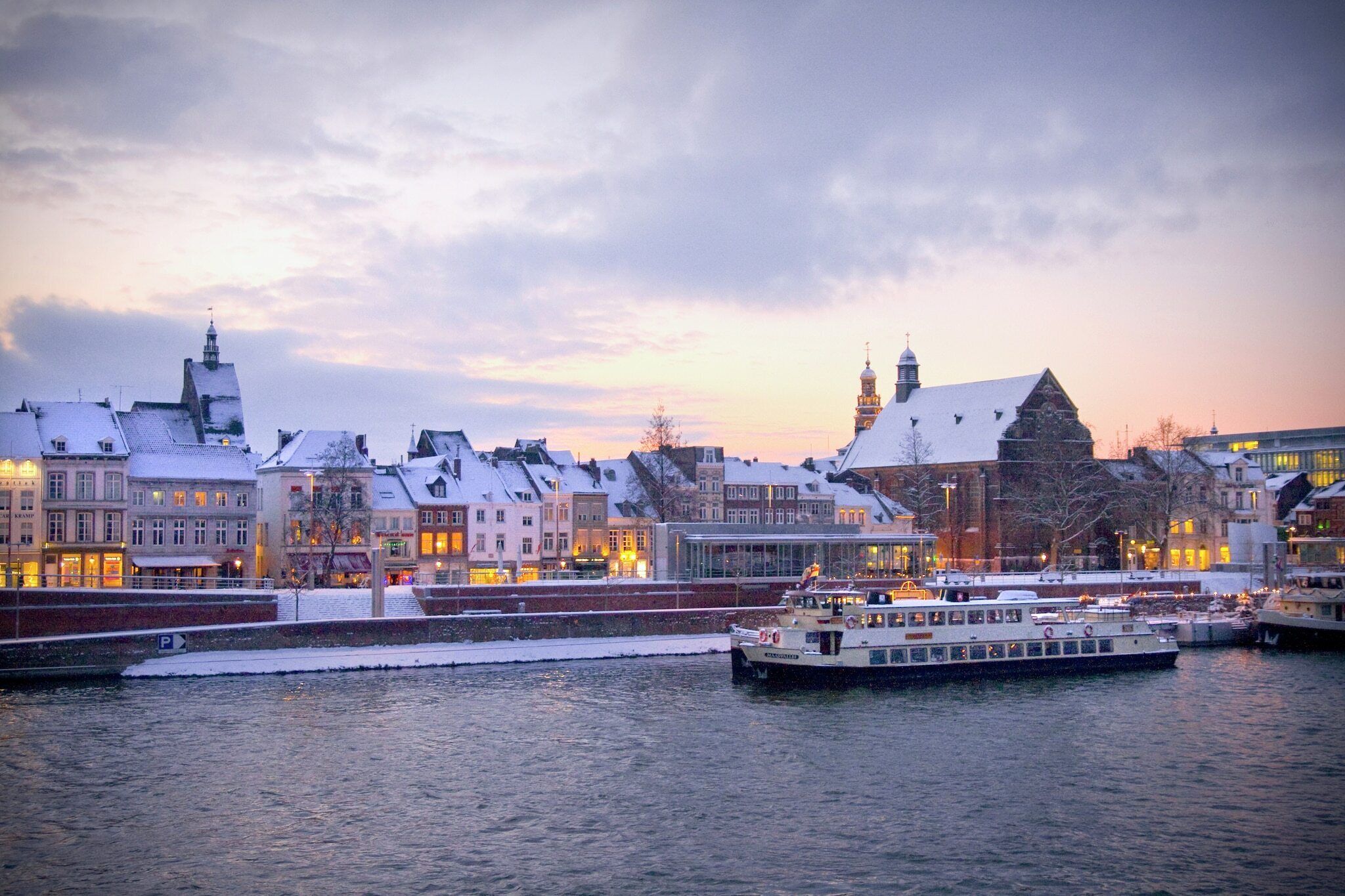 A waterfront cityscape with snow-covered buildings and a river.