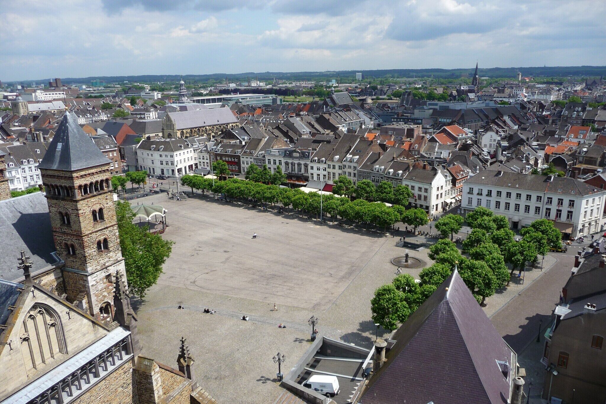 Une place historique, dominée par le clocher d’une église remarquable, entourée de bâtiments traditionnels et bordée d’une vaste place publique.