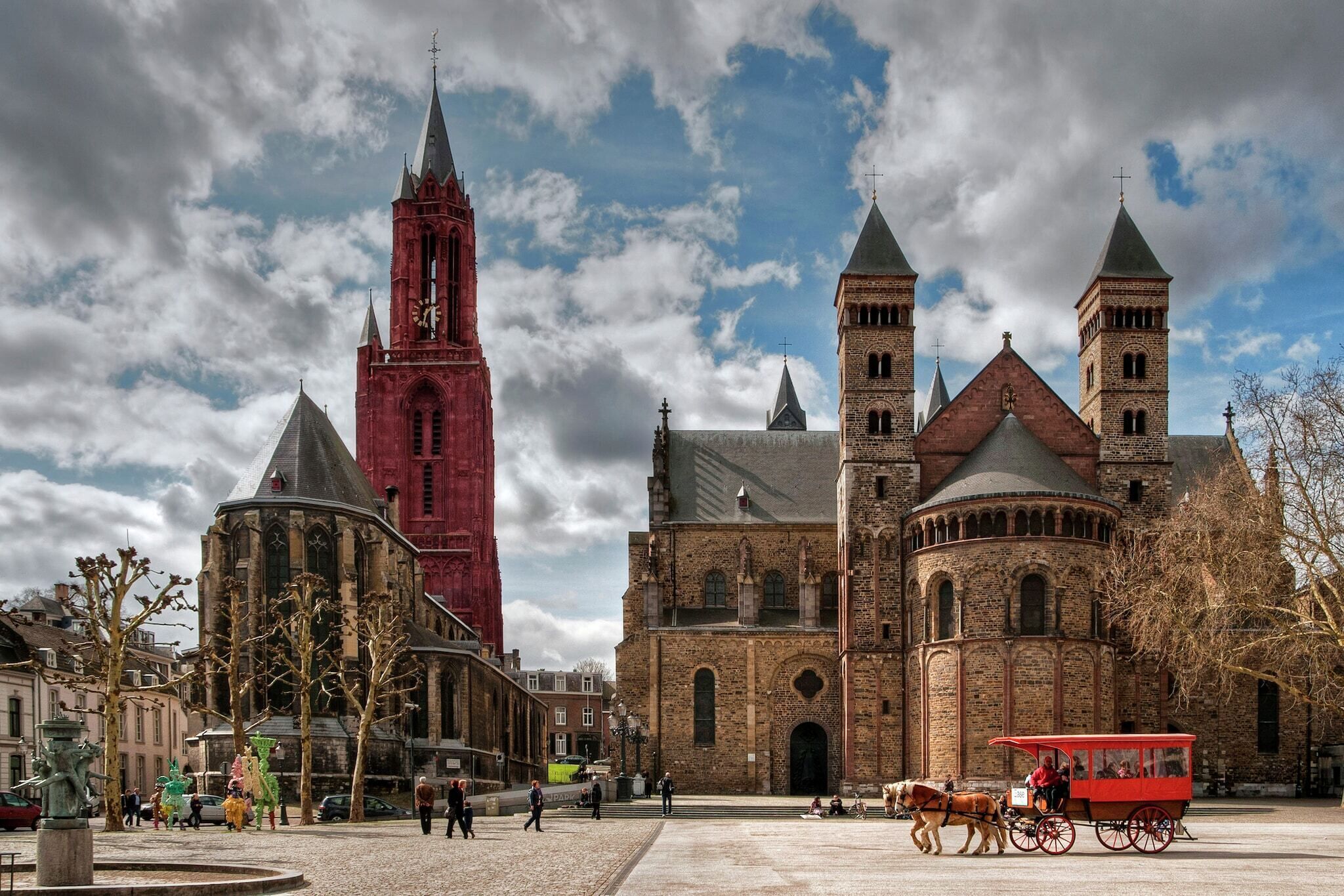 Eine historische Kirche mit einem markanten Turm und ein rot gefasstes Gebäude daneben.