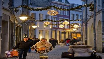 Una strada acciottolata con persone che passeggiano, decorata con luci e ghirlande.