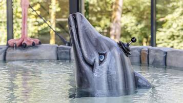 Een dolfijnbeeld in een waterpartij met een mechanische staart en een mechanisch hoofd.