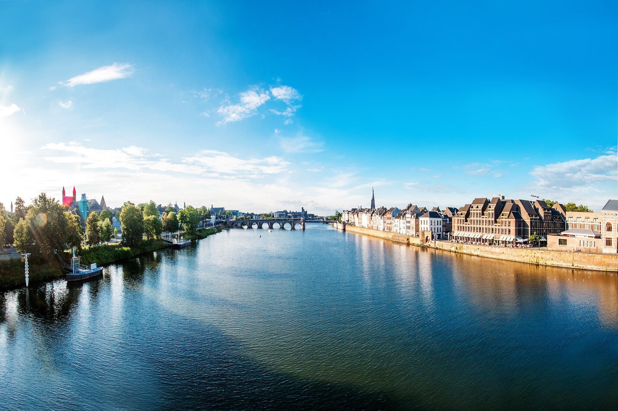A river with a bridge, historic buildings, and a tower in the background.