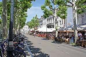 A street lined with trees and parked bicycles, with outdoor seating at cafes and restaurants. - Villa in Maastricht with Sauna & Bubble Bath (Maastricht)