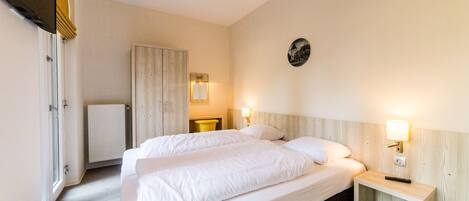 A hotel room with a large bed, bedside tables, a wall-mounted TV, and a radiator.