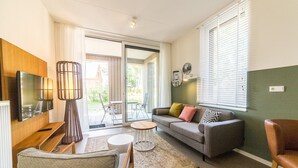 Ett modernt vardagsrum med en soffa, en tv, ett soffbord och en matplats.