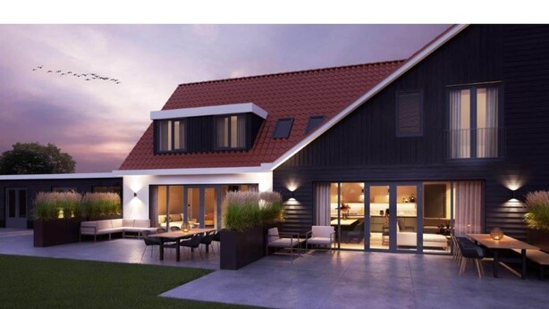 Ett modernt hus med en stor uteplats, utomhusmöbler och en väl upplyst interiör.